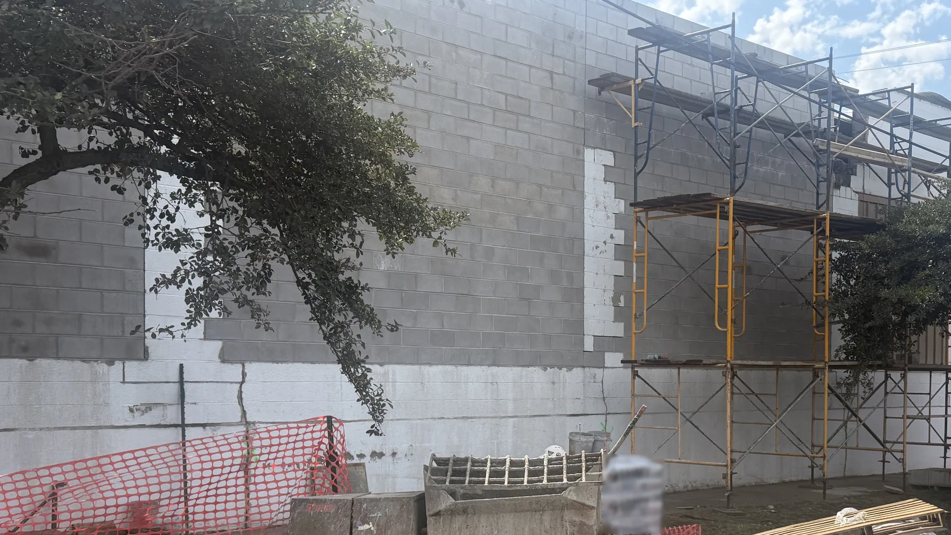 Concrete block wall on a commercial building with steel scaffolding and a mortar mixer at the base, block walls