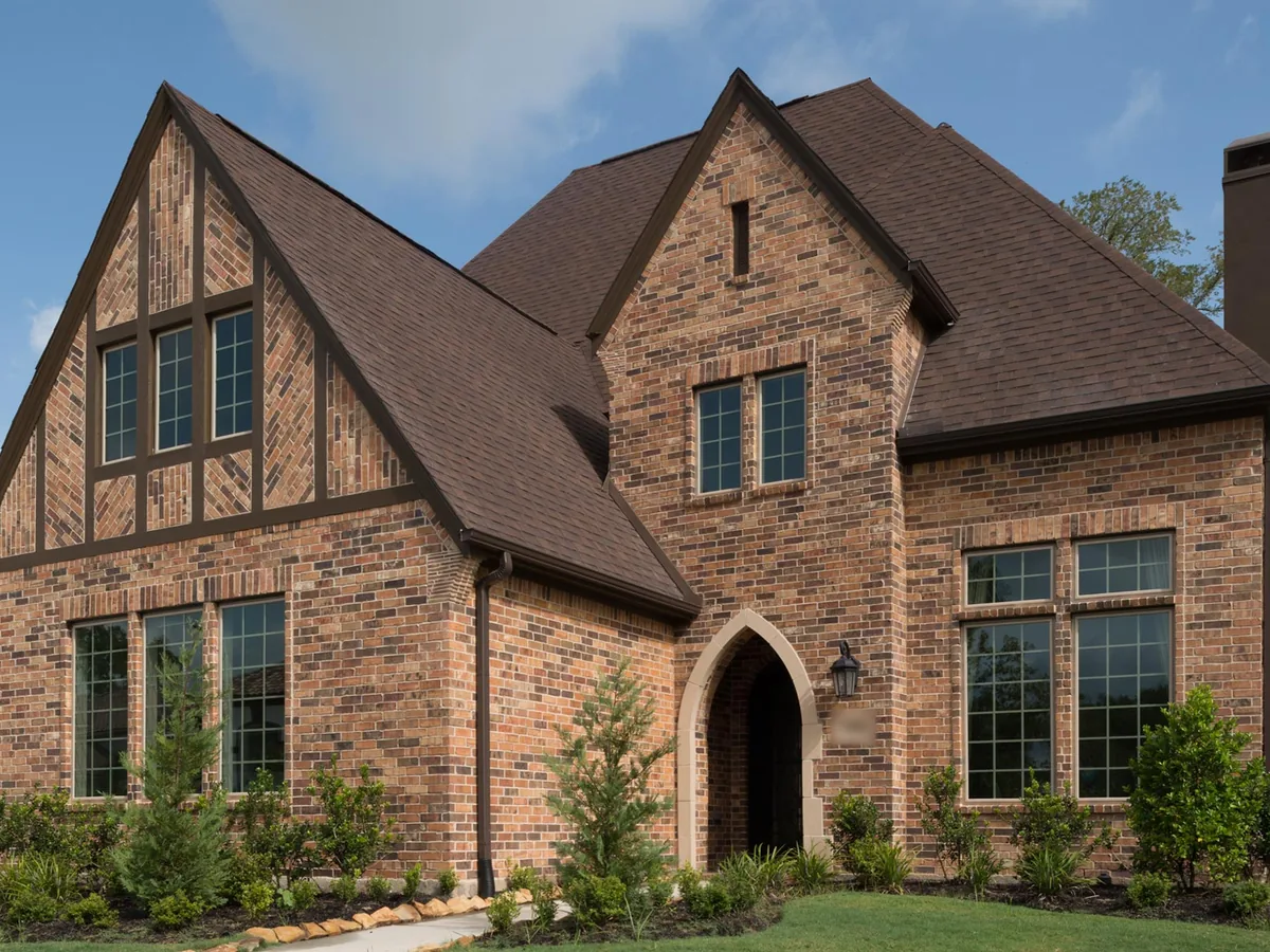 Two-story brick house with steep gables, arched entry and brick window surrounds, brick masonry