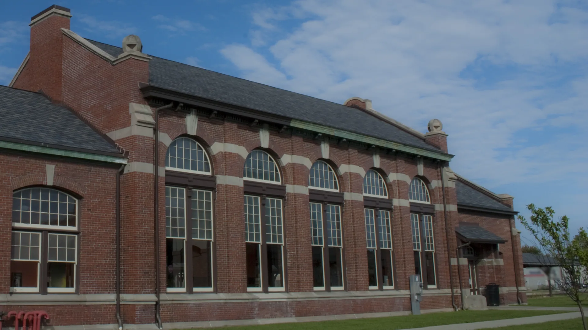 Historic red brick railroad depot with tall arched windows and limestone trim, brick masonry