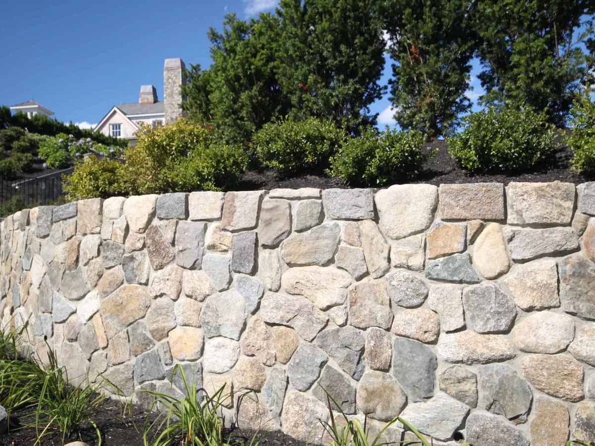 Mortared fieldstone garden wall holding a raised planting bed, stone masonry